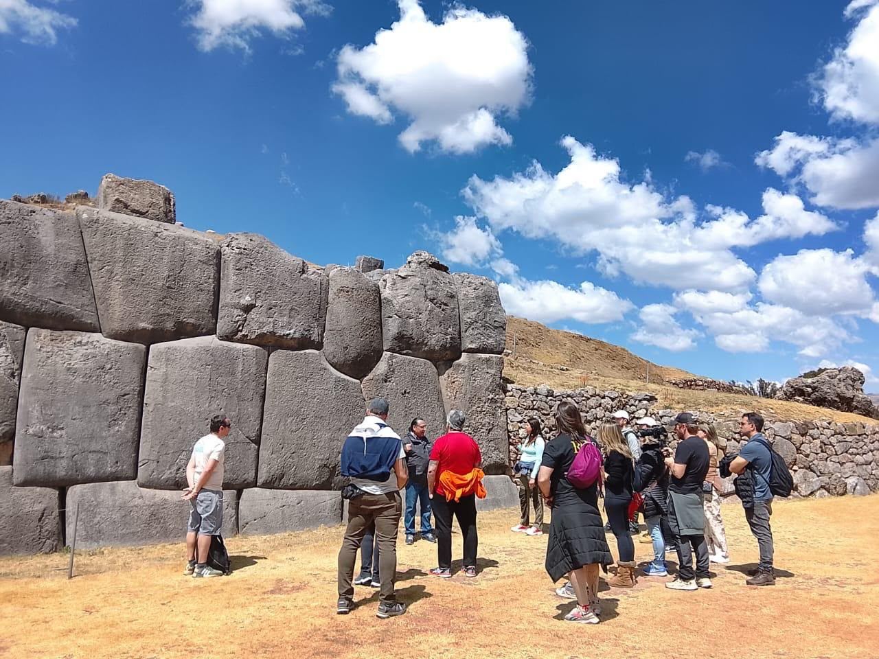 O grupo reunido diante da muralha megalítica de pedras gigantes perfeitamente encaixadas, ouvindo o guia